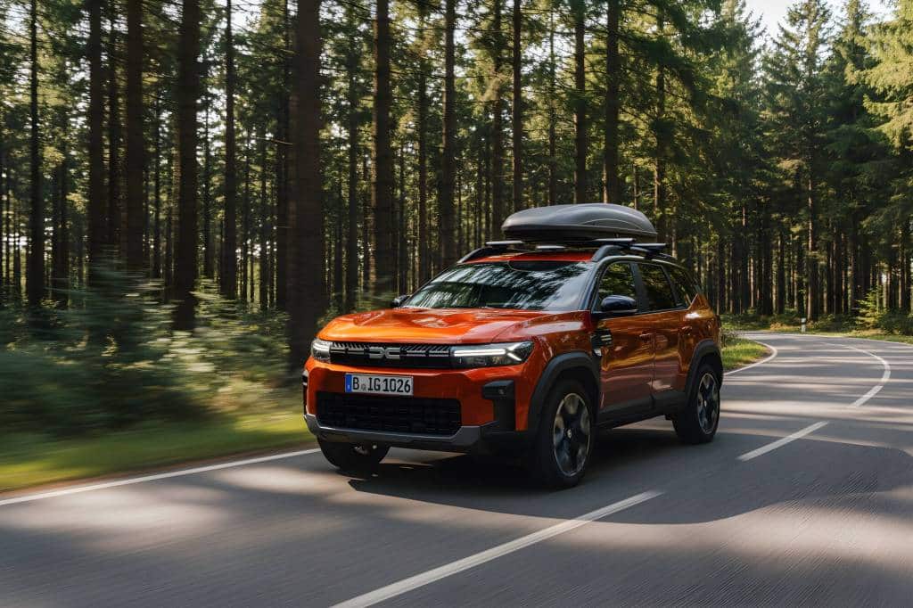 Orangefarbener Dacia Bigster mit Dachbox im Wald